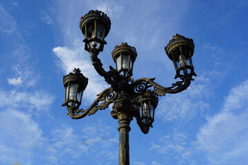 Fototapeta na wymiar Top of street lamp against blue sky 