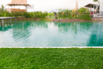 Outdoor swimming pool with green grass and bokeh background.
