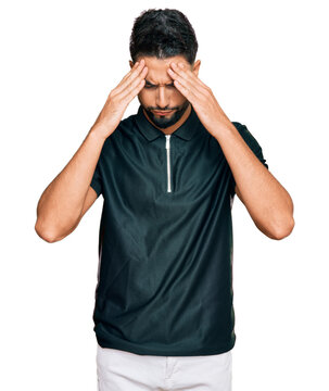 Young man with beard wearing sportswear with hand on head for pain in head because stress. suffering migraine.