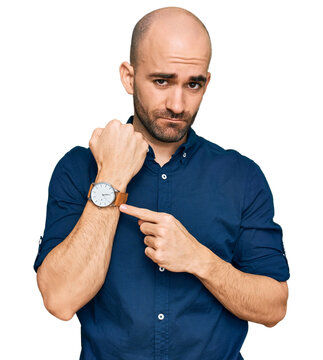 Young hispanic man wearing casual clothes in hurry pointing to watch time, impatience, looking at the camera with relaxed expression