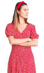 Young beautiful girl wearing dress and diadem looking to the side with arms crossed convinced and confident