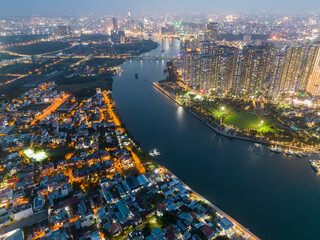 Naklejka premium Aerial view of a Ho Chi Minh City, Vietnam with development buildings, transportation, energy power infrastructure. Financial and business centers. Sunset to night.