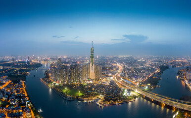 Fototapeta premium Aerial view of a Ho Chi Minh City, Vietnam with development buildings, transportation, energy power infrastructure. Financial and business centers. Sunset to night.