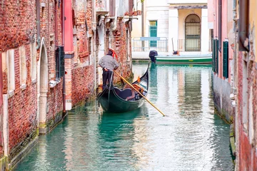 Fotobehang Gondels Venetian gondolier punting gondola through green canal waters of Venice Italy