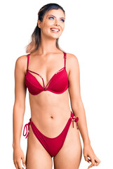 Obraz premium Young beautiful woman wearing bikini looking away to side with smile on face, natural expression. laughing confident.