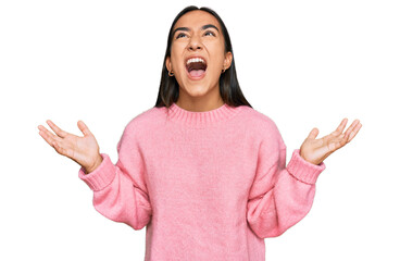 Young asian woman wearing casual winter sweater crazy and mad shouting and yelling with aggressive expression and arms raised. frustration concept.