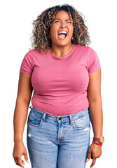 Young african american plus size woman wearing casual clothes angry and mad screaming frustrated and furious, shouting with anger. rage and aggressive concept.