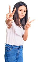 Beautiful child girl wearing casual clothes smiling looking to the camera showing fingers doing victory sign. number two.