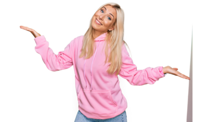 Young blonde woman wearing casual sweatshirt clueless and confused expression with arms and hands raised. doubt concept.