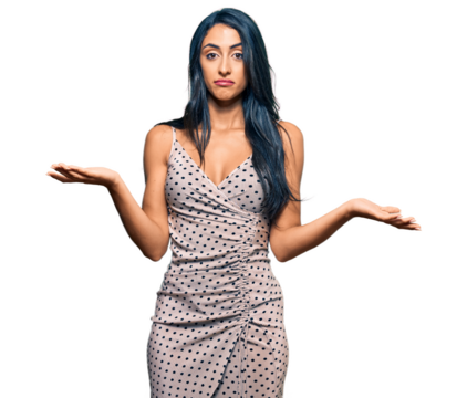 Beautiful hispanic woman wearing summer dress clueless and confused expression with arms and hands raised. doubt concept.
