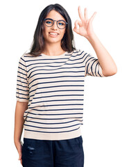 Obraz na płótnie Canvas Brunette teenager girl wearing casual clothes and glasses smiling positive doing ok sign with hand and fingers. successful expression.