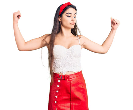 Brunette teenager girl wearing elegant look showing arms muscles smiling proud. fitness concept.