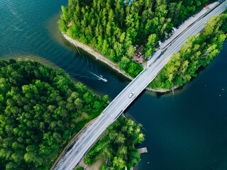 Aerial view of bridge asphalt road with car and blue water lake with boat. Beautiful summer landscape in Finland.