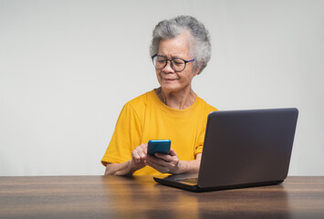 Senior woman with short white hair using a smartphone while sitting at the table.