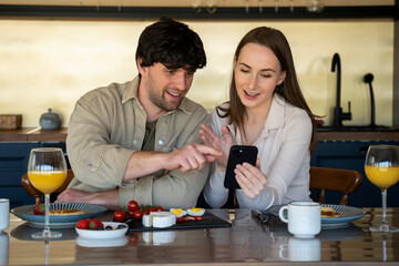 Young beautiful couple in the dining room. A family of two people use a tablet computer while sitting at the dining table
