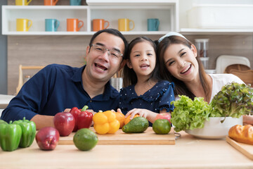 Happy Asian father, mother and daughter in kitchen at home. Happy Asian family spending time together in kitchen at home