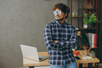 Successful smiling happy young employee business Indian man wears casual blue checkered glasses...