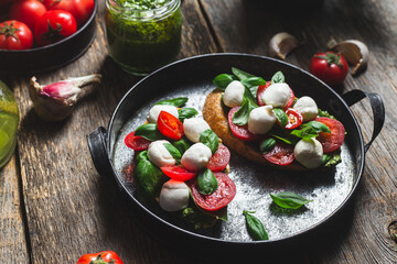 Bruschetta with mozzarella, tomatoes, basil and pesto in a plate. Bruschetta Caprese