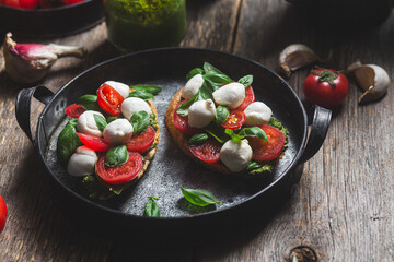 Bruschetta with mozzarella, tomatoes, basil and pesto in a plate. Bruschetta Caprese
