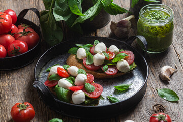Bruschetta with mozzarella, tomatoes, basil and pesto in a plate. Bruschetta Caprese