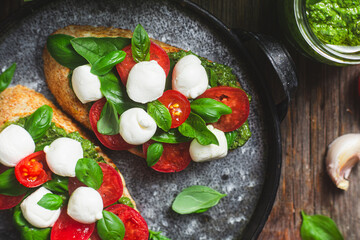 Bruschetta with mozzarella, tomatoes, basil and pesto in a plate. Bruschetta Caprese