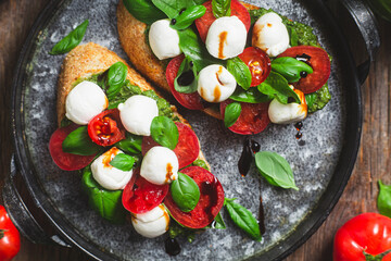 Bruschetta with mozzarella, tomatoes, basil and pesto in a plate. Bruschetta Caprese