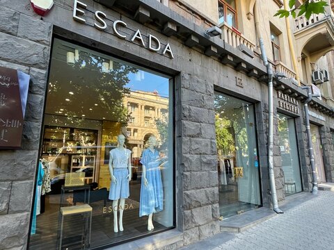 Boutiques of Escada and Fabiana Filippi fashion brands. Summer European street. Facade of old building. Latest clothes collections on mannequins in shopwindow. Shopping in Europe. 