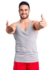 Young handsome man wearing swimwear and sleeveless t-shirt looking at the camera smiling with open arms for hug. cheerful expression embracing happiness.