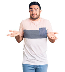 Young handsome man wearing casual clothes clueless and confused expression with arms and hands...
