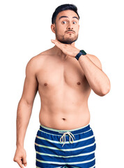 Fototapeta premium Young handsome man wearing swimwear cutting throat with hand as knife, threaten aggression with furious violence