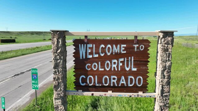 Welcome to Colorful Colorado sign in grassland. Aerial rising shot of state road sign welcoming people to CO.
