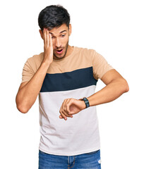Young handsome man wearing casual clothes looking at the watch time worried, afraid of getting late