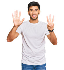 Naklejka premium Young handsome man wearing casual white tshirt showing and pointing up with fingers number eight while smiling confident and happy.