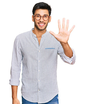 Young handsome man wearing casual clothes and glasses showing and pointing up with fingers number five while smiling confident and happy.