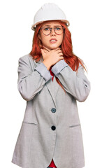 Young redhead woman wearing architect hardhat shouting and suffocate because painful strangle. health problem. asphyxiate and suicide concept.