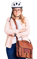 Young caucasian woman wearing bike helmet and leather bag skeptic and nervous, disapproving expression on face with crossed arms. negative person.
