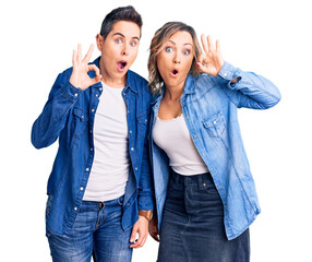 Couple of women wearing casual clothes looking surprised and shocked doing ok approval symbol with fingers. crazy expression