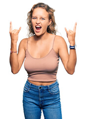 Beautiful caucasian woman wearing casual clothes shouting with crazy expression doing rock symbol with hands up. music star. heavy concept.