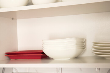 White dishes plates inside open white kitchen cabinet