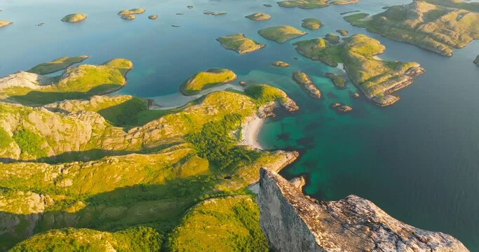 Drone reveal scenic arctic beach from pointed vertical cliff in midnight sun