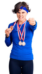 Beautiful young woman with short hair wearing winner medals annoyed and frustrated shouting with anger, yelling crazy with anger and hand raised