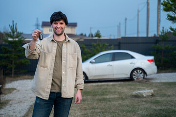 Happy buyer holds the keys near a new white car. 