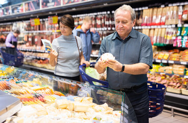 Elderly man choose cheese in supermarket
