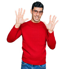 Naklejka premium Handsome hispanic man wearing casual clothes and glasses showing and pointing up with fingers number ten while smiling confident and happy.