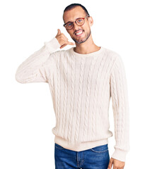 Fototapeta premium Young handsome man wearing casual clothes and glasses smiling doing phone gesture with hand and fingers like talking on the telephone. communicating concepts.