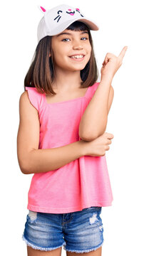 Young little girl with bang wearing funny kitty cap smiling happy pointing with hand and finger to the side