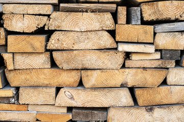 Background from round wooden trunks. Wooden logs and stumps. Winter stocks of firewood.