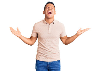 Fototapeta premium Young handsome latin man wearing casual clothes celebrating mad and crazy for success with arms raised and closed eyes screaming excited. winner concept