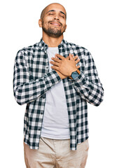 Hispanic adult man wearing casual clothes smiling with hands on chest with closed eyes and grateful gesture on face. health concept.