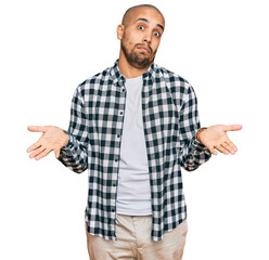 Hispanic adult man wearing casual clothes clueless and confused expression with arms and hands...